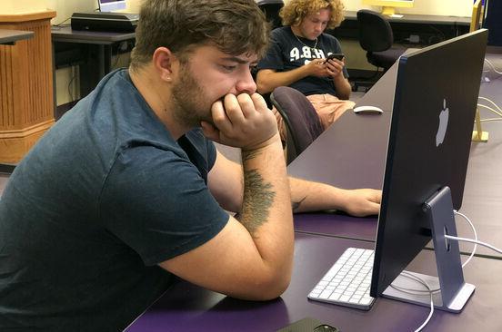 A male student works on a computer in a computer lab